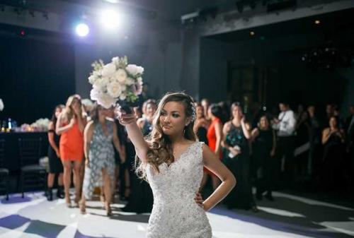 bride-getting-ready-to-throw-bouquet-inside-event-venue-crowd-behind